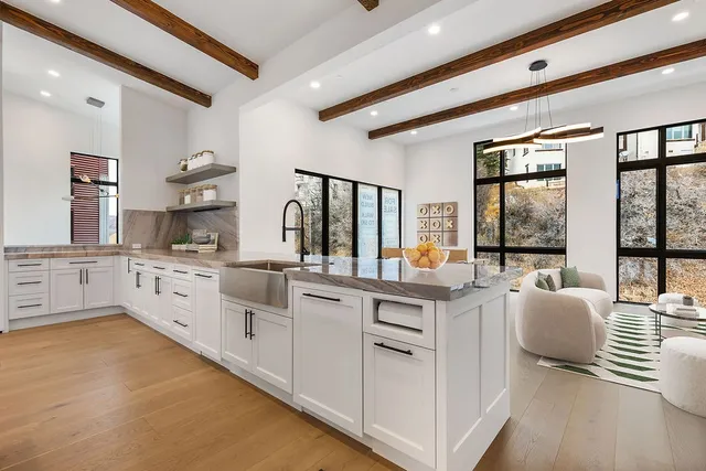 a large white kitchen with granite countertop a large window and white cabinets