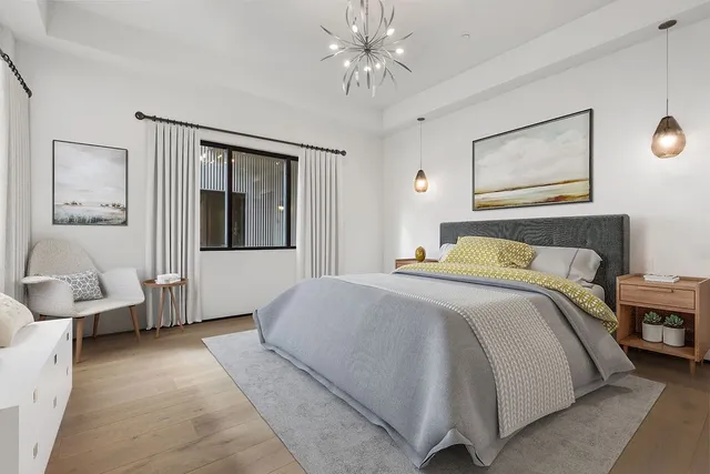 a bedroom with a large bed couch and two windows