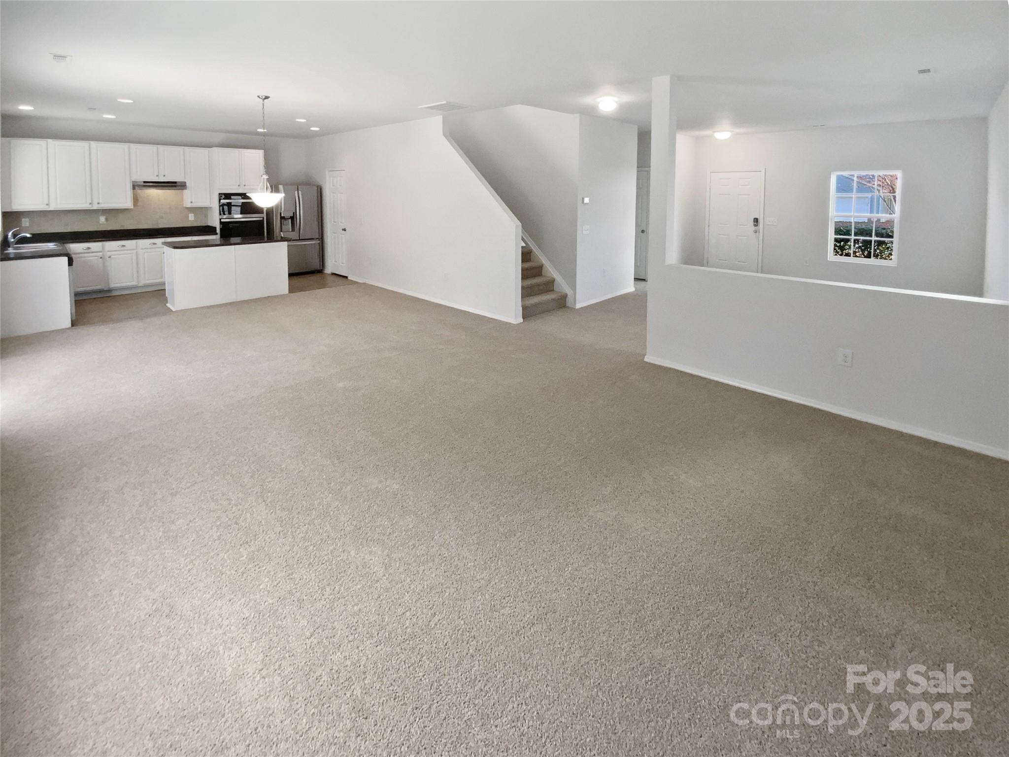 4418 Kiddle Lane Monroe, NC 28110 - Photo 3 of 19 an empty room with kitchen view and a refrigerator