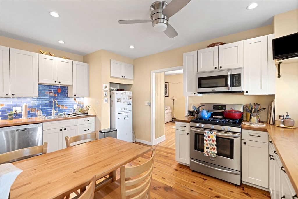 59 7th Street Cambridge, MA 02141 - Photo 3 of 26 a kitchen with stainless steel appliances granite countertop a stove top oven a refrigerator a sink and white cabinets with wooden floor