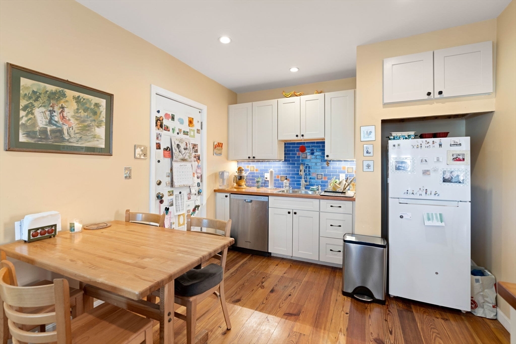 59 7th Street Cambridge, MA 02141 - Photo 5 of 26 a kitchen with stainless steel appliances a stove a refrigerator and white cabinets with wooden floor