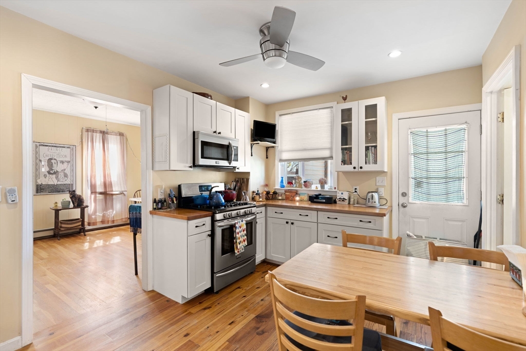 59 7th Street Cambridge, MA 02141 - Photo 7 of 26 a kitchen with stainless steel appliances granite countertop a stove top oven a sink dishwasher a dining table and chairs with wooden floor