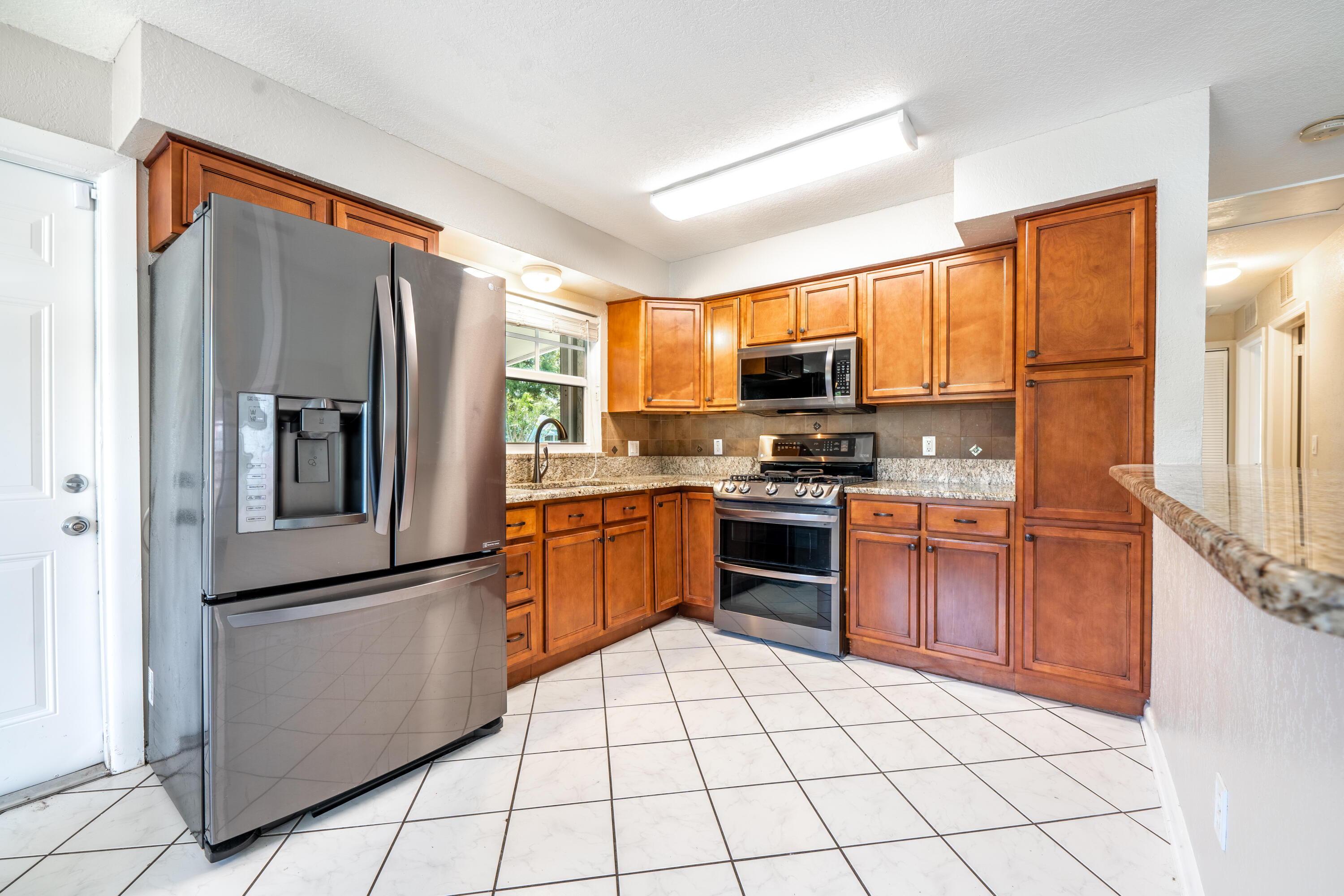 1219 South 10th Street Fort Pierce, FL 34950 - Photo 3 of 29 a kitchen with stainless steel appliances a refrigerator sink and microwave
