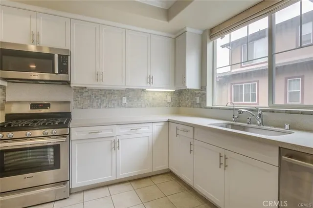 a kitchen with white cabinets and a window