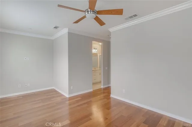 an empty room with wooden floor fan and windows