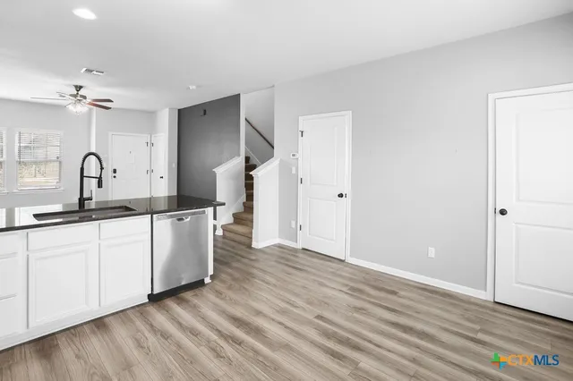 a kitchen with granite countertop a sink cabinets and wooden floor