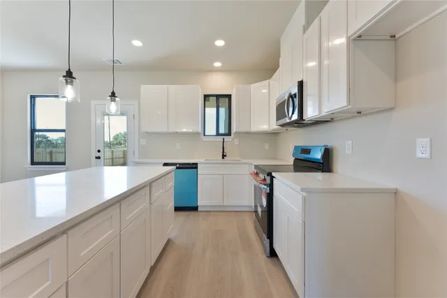 a kitchen with stainless steel appliances granite countertop a sink a stove and a refrigerator