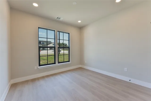 an empty room with wooden floor and windows