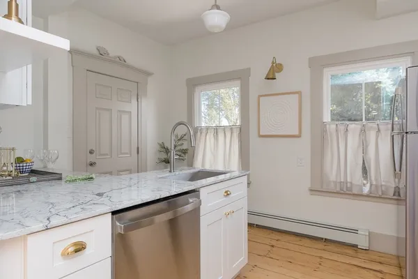 a kitchen with granite countertop a sink cabinets and wooden floor