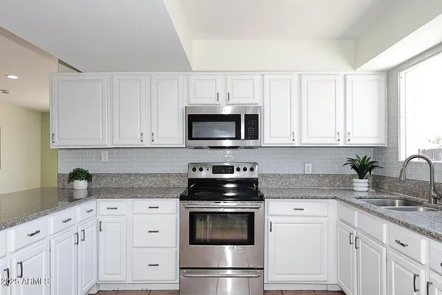 a kitchen with white cabinets and stainless steel appliances