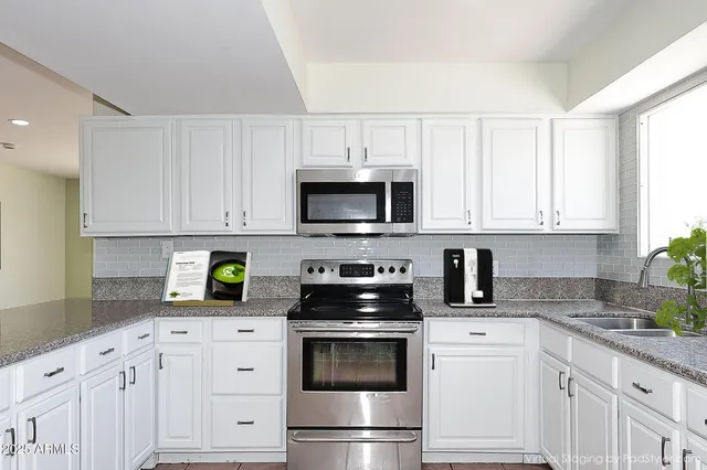 a kitchen with white cabinets and stainless steel appliances