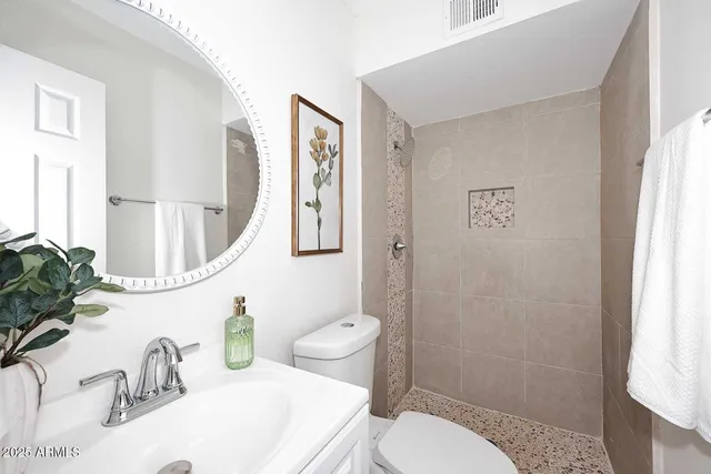 a bathroom with a granite countertop sink mirror vanity and toilet