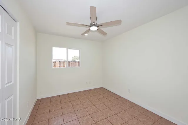 an empty room with a ceiling fan and a window