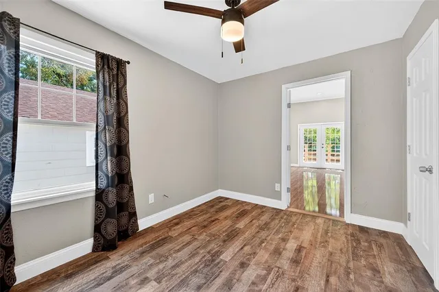 a view of an empty room with wooden floor and a window