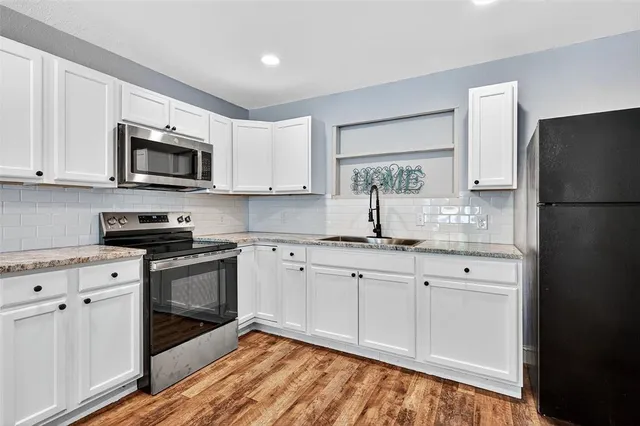 a kitchen with granite countertop white cabinets white stainless steel appliances and a sink