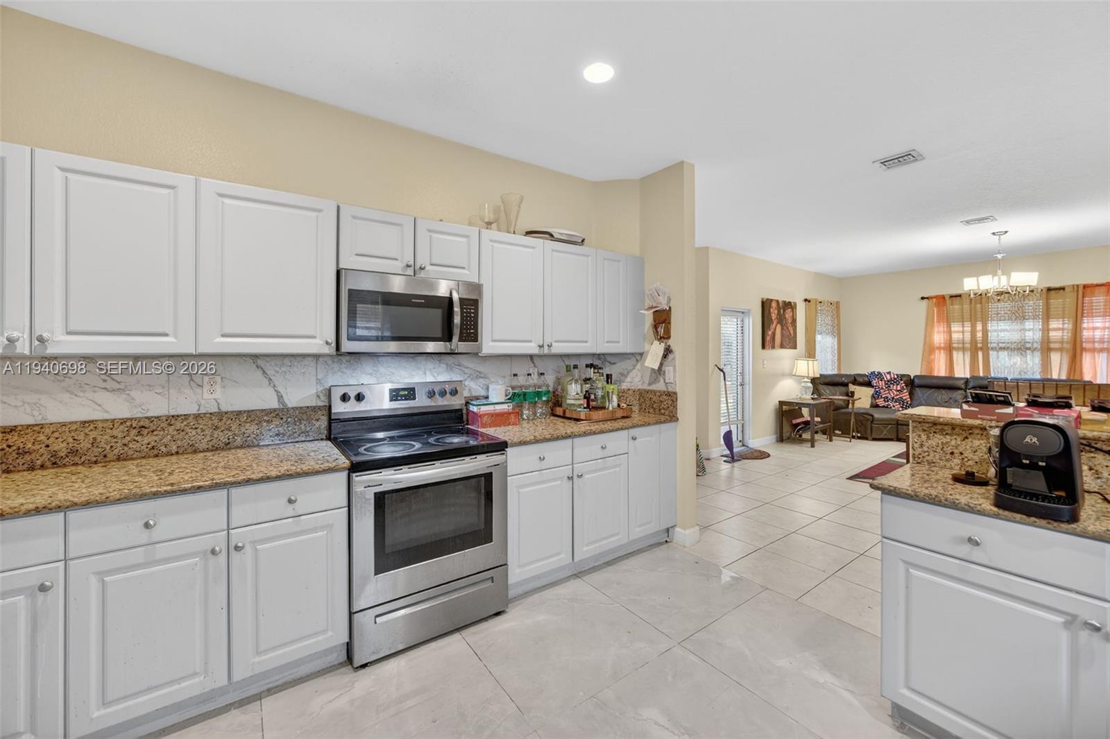 367 Northeast 36th Avenue Road Homestead, FL 33033 - Photo 12 of 36 a kitchen with granite countertop a stove a sink and a microwave