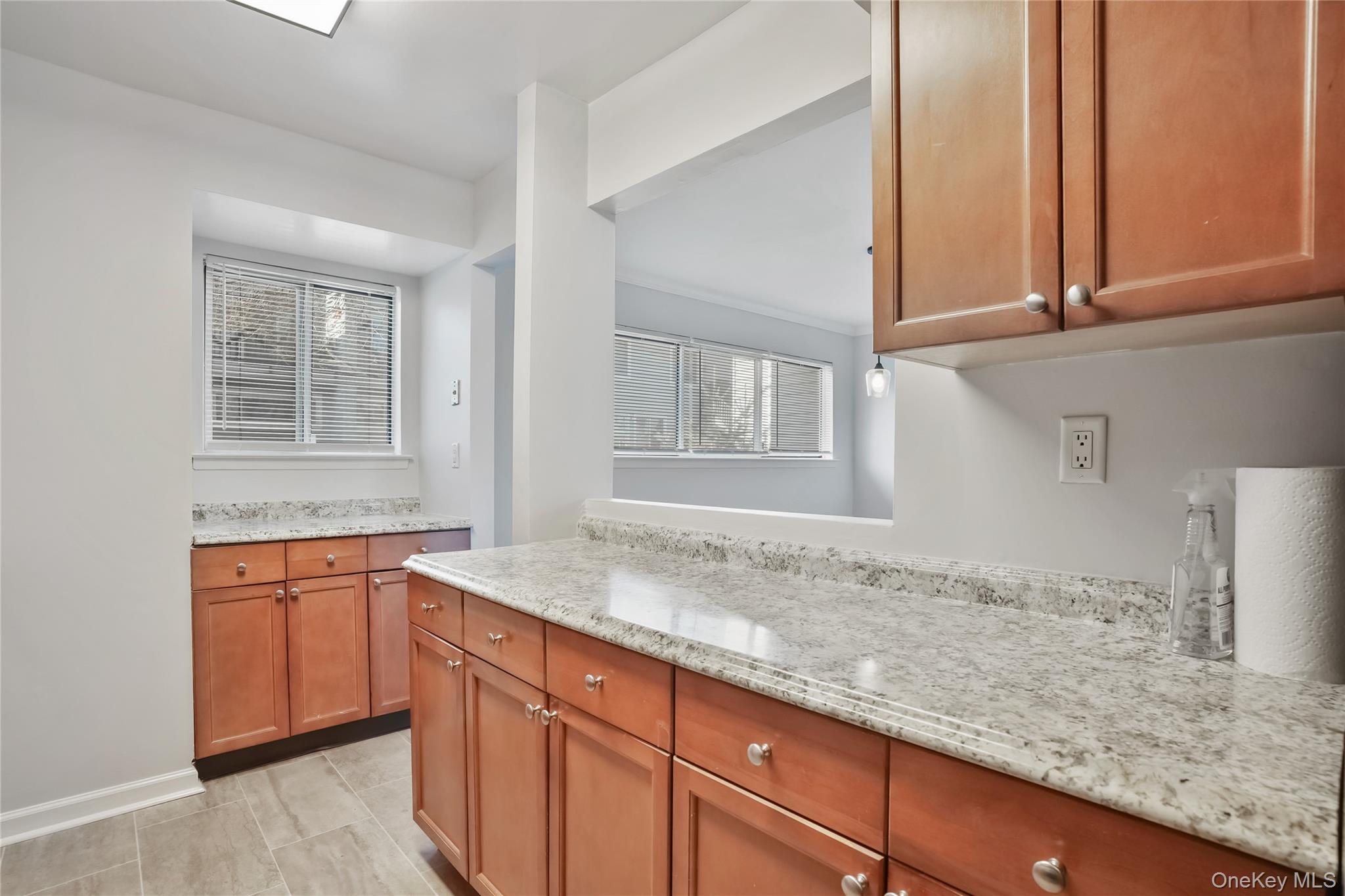 208 Harris Road, Unit HA3 Bedford, NY 10507 - Photo 11 of 41 Kitchen with brown cabinetry, light stone countertops, and light tile patterned floors