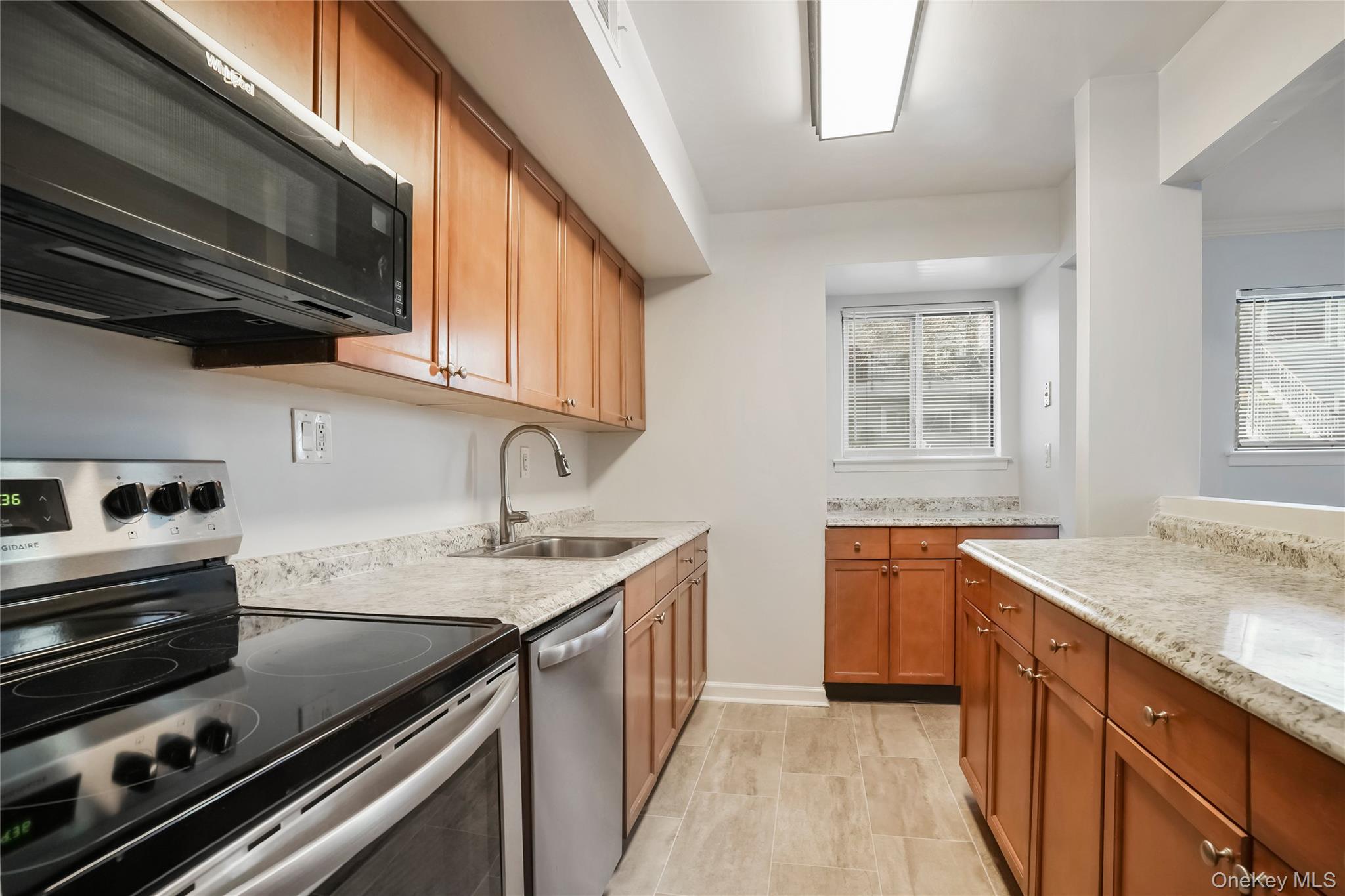 208 Harris Road, Unit HA3 Bedford, NY 10507 - Photo 12 of 41 Kitchen featuring appliances with stainless steel finishes, brown cabinetry, and light stone countertops