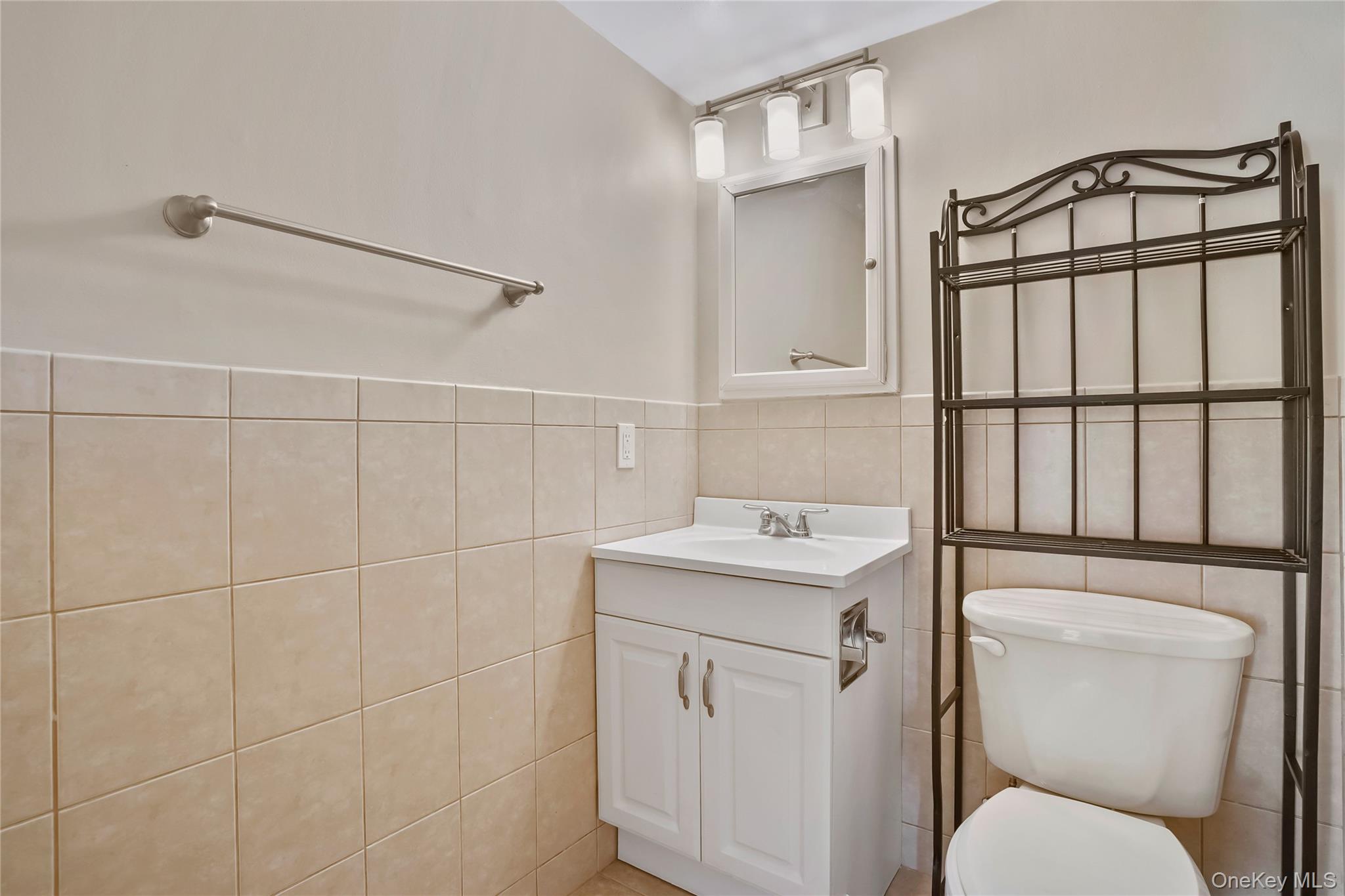 208 Harris Road, Unit HA3 Bedford, NY 10507 - Photo 23 of 41 Half bath with vanity, tile walls, and wainscoting