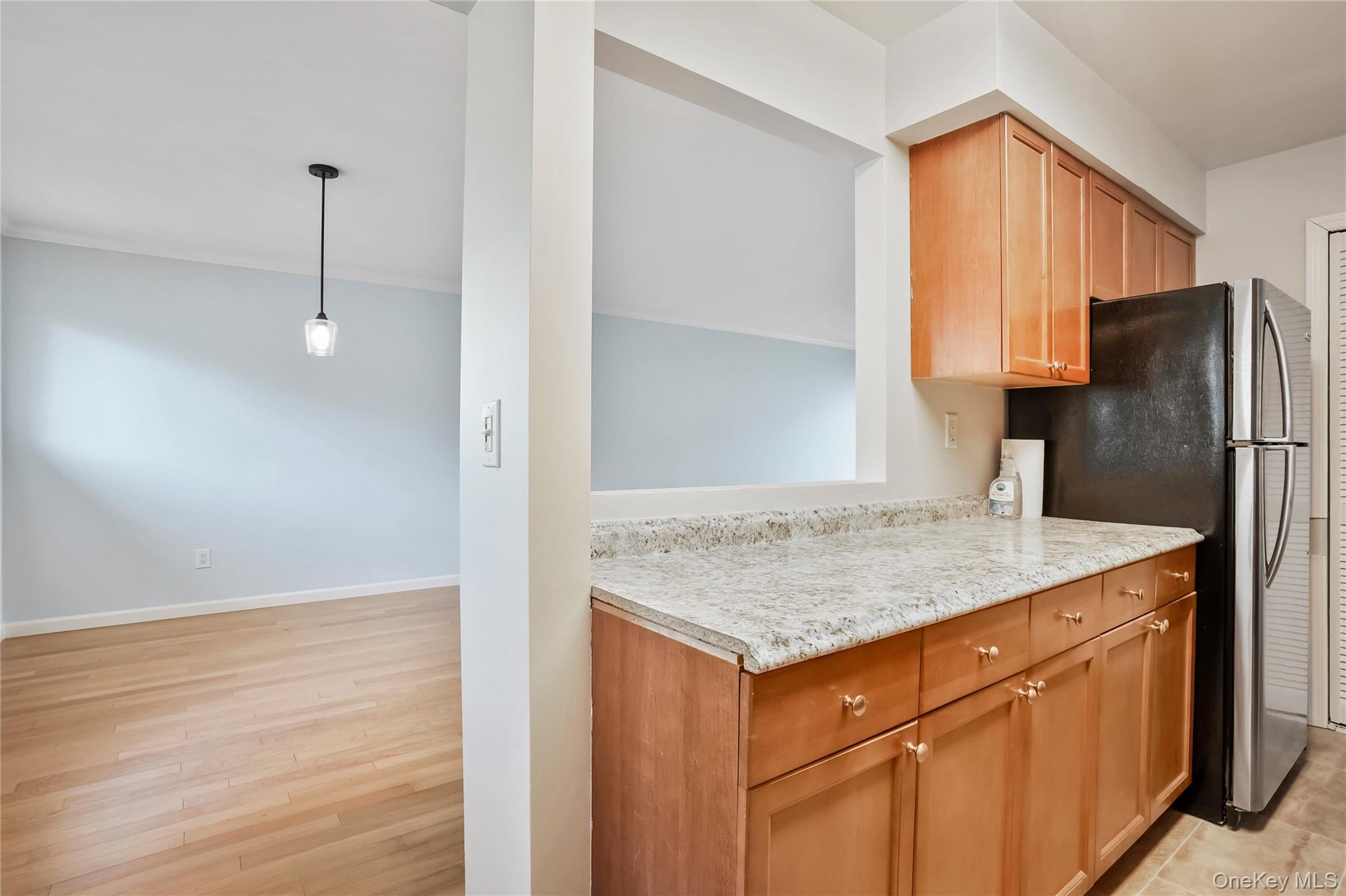 208 Harris Road, Unit HA3 Bedford, NY 10507 - Photo 9 of 41 Kitchen featuring pendant lighting, freestanding refrigerator, brown cabinetry, and light wood-style flooring