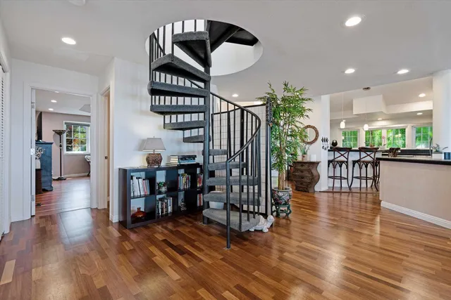 a view of a hallway with wooden floor stairs and a livingroom
