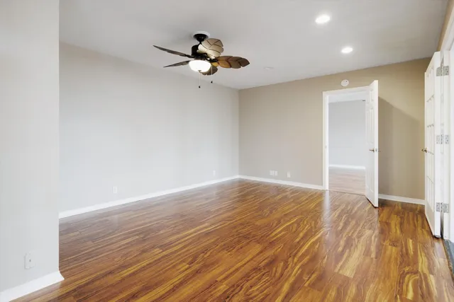 a view of empty room with wooden floor and fan