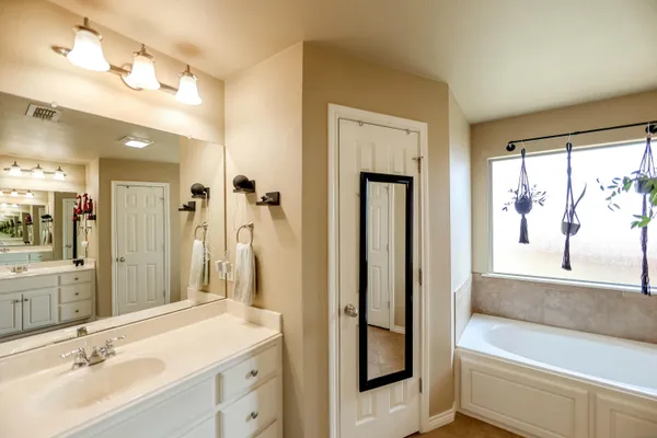 a bathroom with a tub sink and mirror