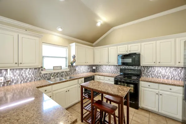 a kitchen with stainless steel appliances kitchen island granite countertop a sink a stove a counter space and cabinets