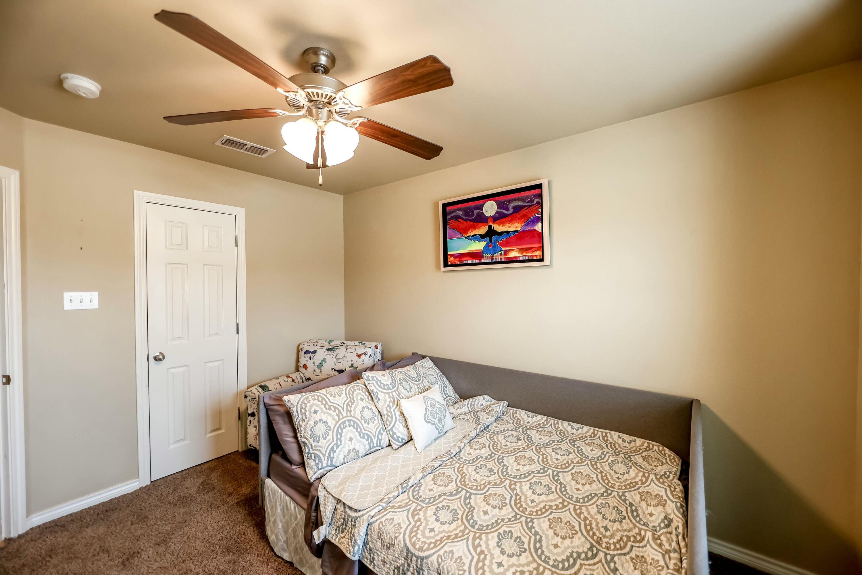 5920 104th Street Lubbock, TX 79424 - Photo 8 of 26 a bedroom with a bed and a chandelier