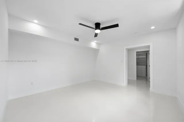 an empty room with a window and a ceiling fan