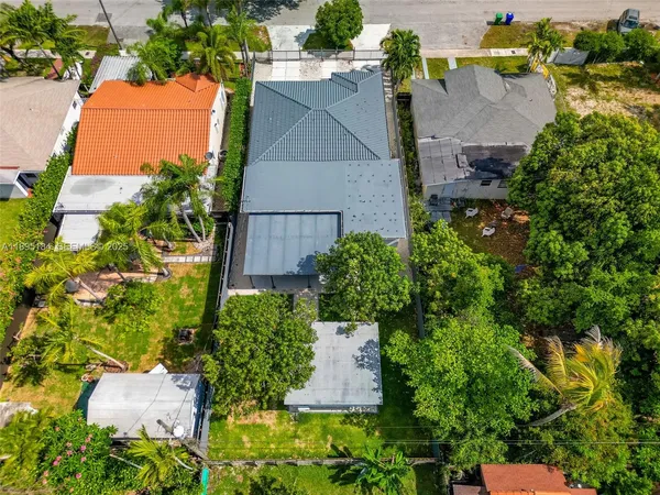 an aerial view of a house with a yard and a large tree