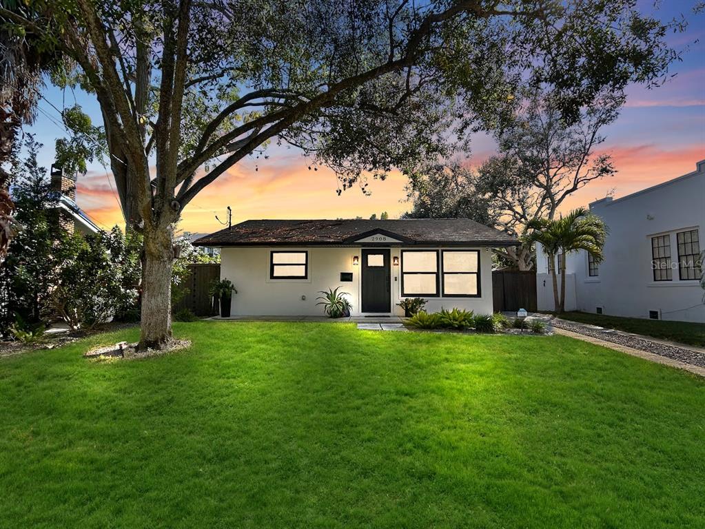 a view of a yard in front of a house with large trees