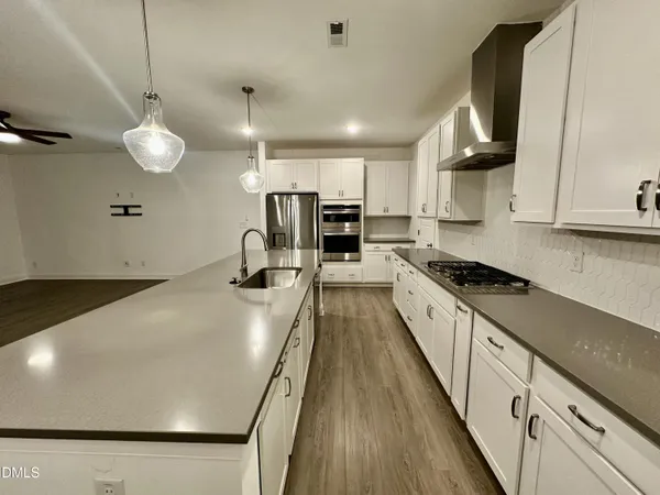 a kitchen with stainless steel appliances a stove a refrigerator a sink and white cabinets