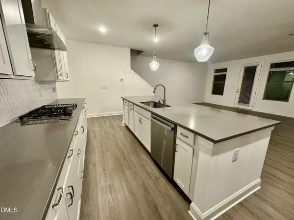 a kitchen with stainless steel appliances granite countertop a sink a stove and a wooden floors