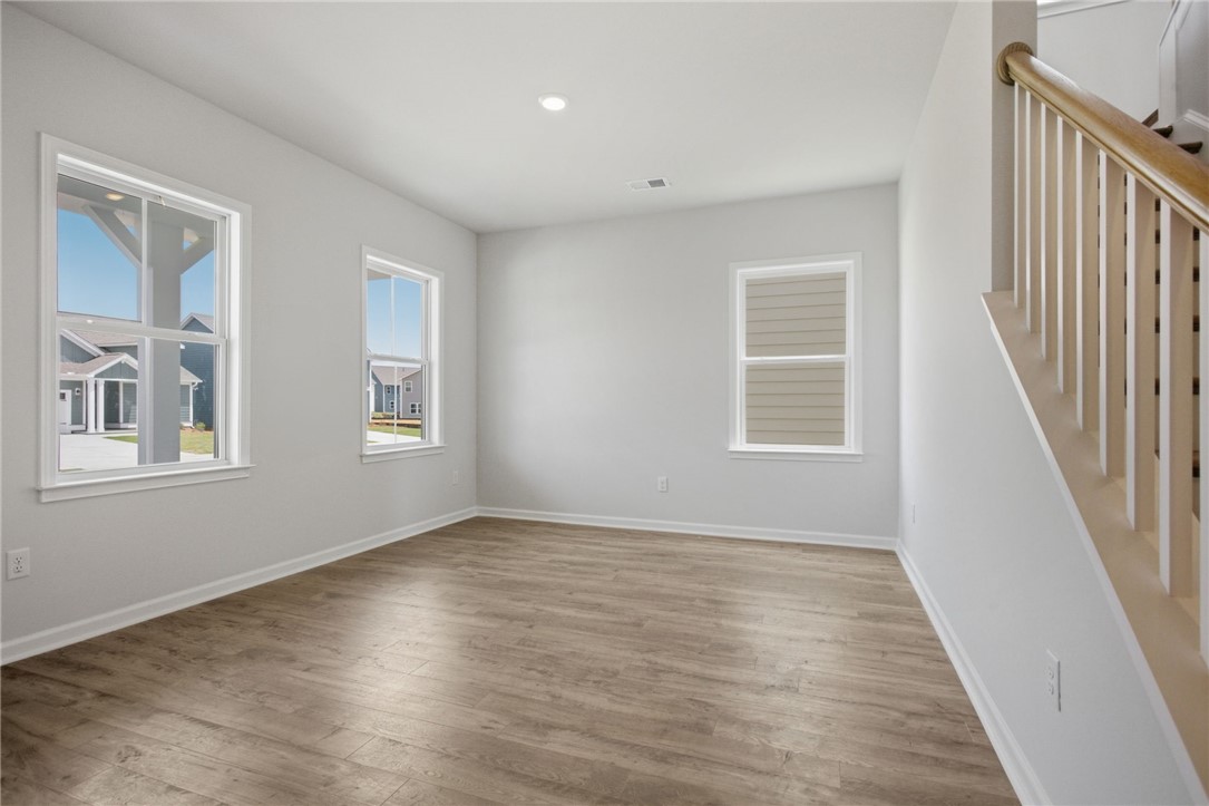 557 Hydrangea Street, Unit LOT 46 Seneca, SC 29678 - Photo 5 of 37 An inviting interior space featuring durable laminate flooring and a well-lit staircase leading to upper levels.