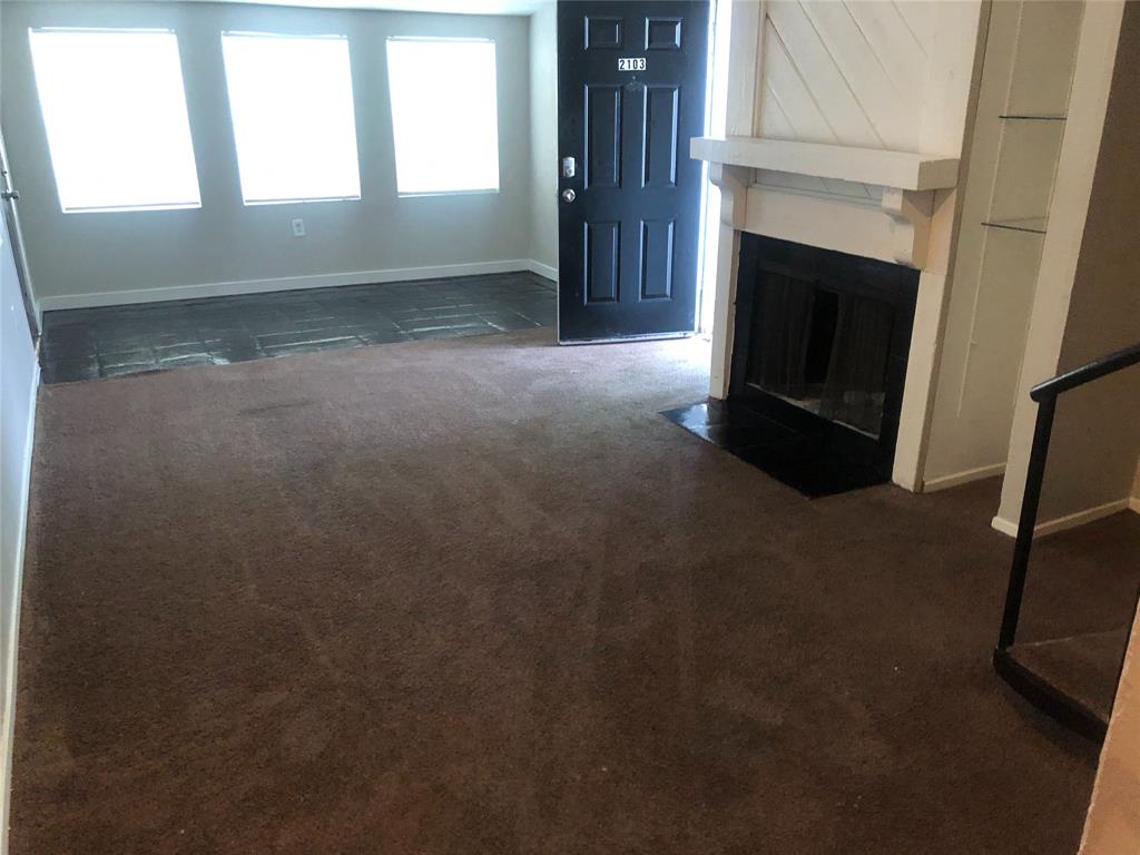 9696 Walnut Street, Unit 2103 Dallas, TX 75243 - Photo 2 of 7 Living area featuring a fireplace with a white mantel, an integrated shelving unit with glass shelves, and a black front door