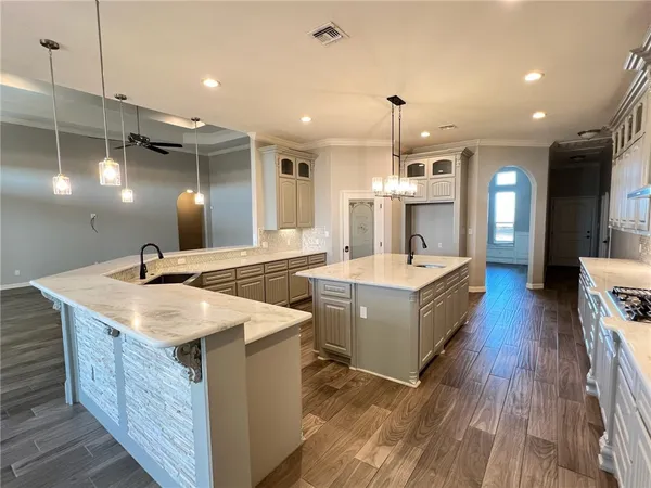 a large kitchen with stainless steel appliances granite countertop a sink a counter space and wooden floors
