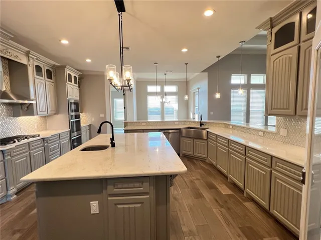 a large kitchen with kitchen island a sink appliances wooden floor and a counter top space