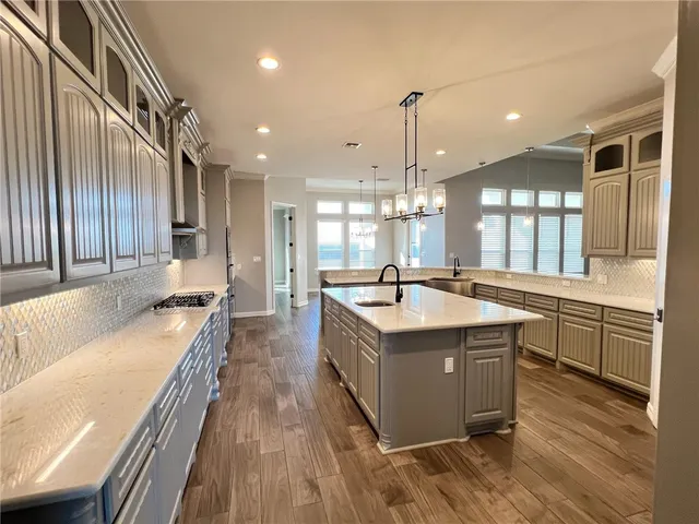 a large kitchen with granite countertop a large center island a sink stainless steel appliances and cabinets