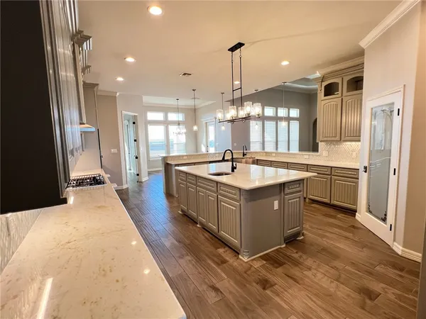 a large white kitchen with a large counter top a sink a window and stainless steel appliances