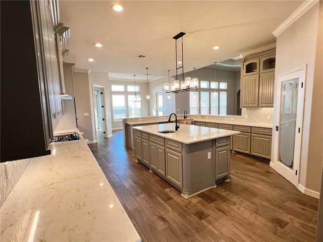 a large white kitchen with a large counter top a sink a window and stainless steel appliances