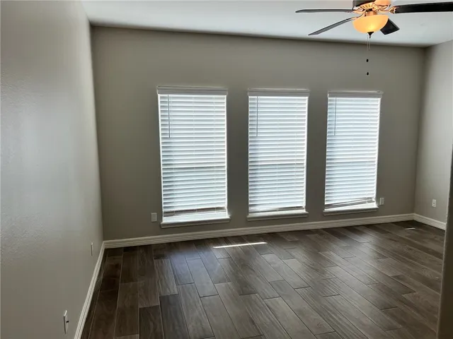 a view of a room with wooden floor and a ceiling fan