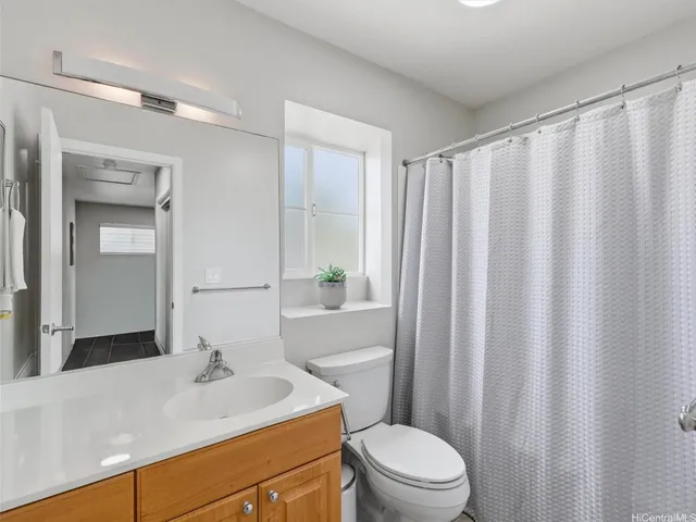 a bathroom with a sink a toilet a mirror and shower curtain