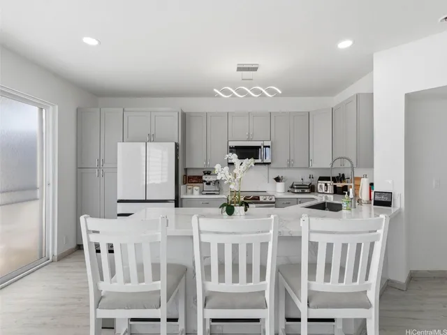 a kitchen with stainless steel appliances a stove a sink refrigerator and white cabinets with wooden floors