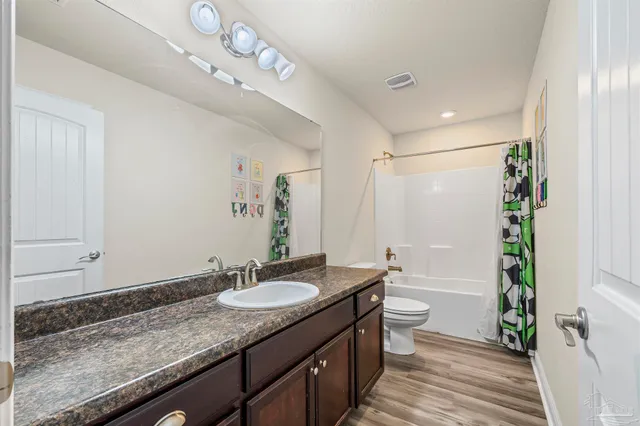 a bathroom with a granite countertop sink a toilet a mirror a vanity and shower