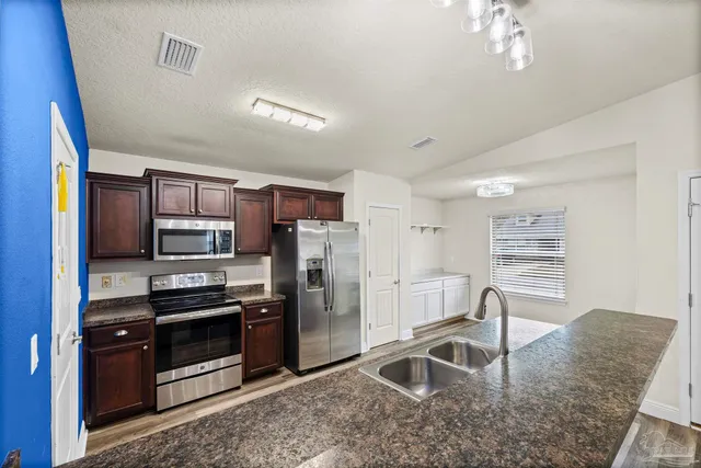 a kitchen with stainless steel appliances granite countertop a refrigerator a stove a sink a oven with a dining table and chairs