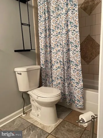 a bathroom with a toilet and a shower curtain