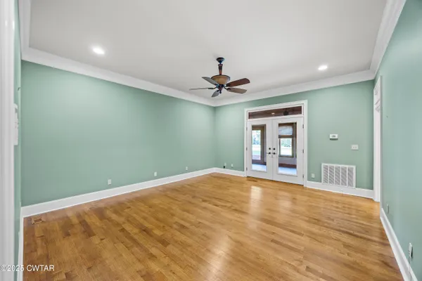 an empty room with windows and ceiling fan