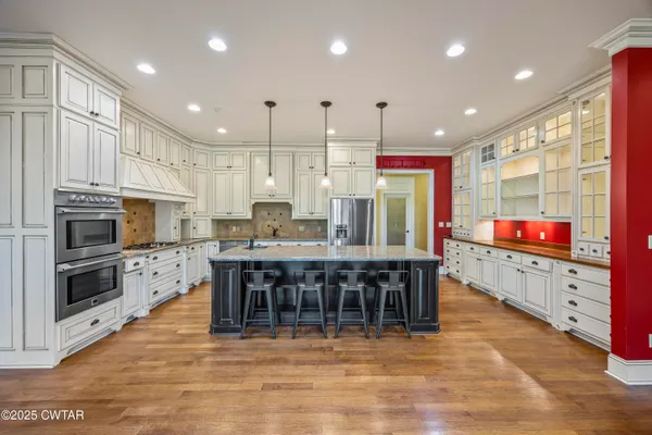 a kitchen with stainless steel appliances kitchen island granite countertop a stove top oven a sink a dining table and chairs