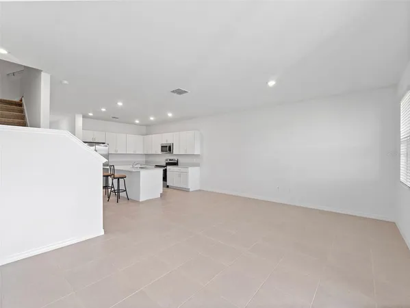 a view of kitchen with kitchen island a sink a stove and a refrigerator with wooden floor